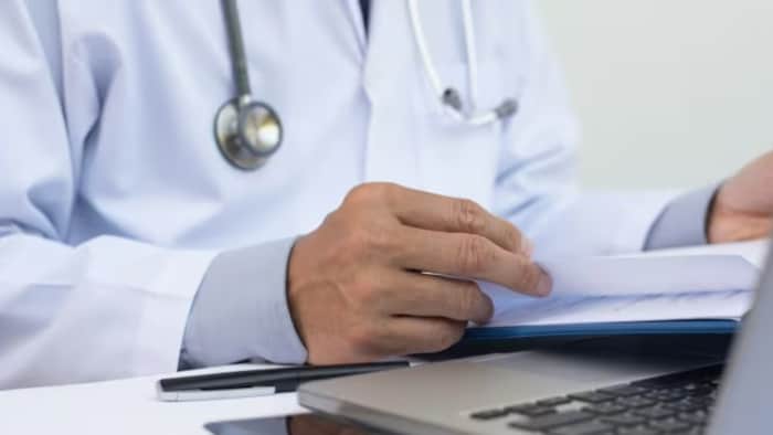 Un médecin tient des feuilles de papier entre ses doigts.