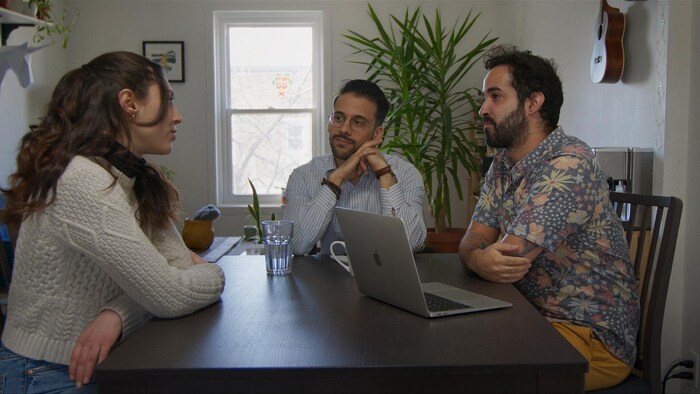 A woman and two men sitting around a table.