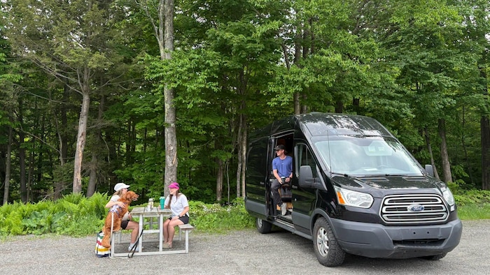 Une van et deux personnes assises à une table à pique-nique.