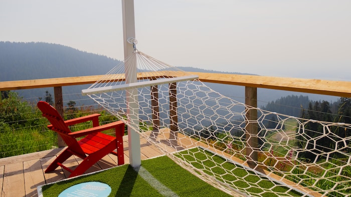 Un hamac suspendu et une chaise à côté, sur une terrasse en montagne.