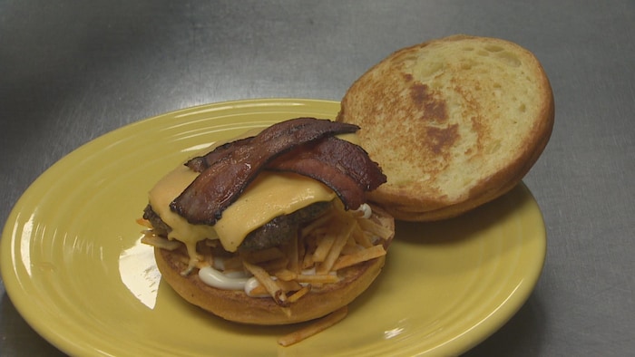 Un burger au fromage avec bacon et croustilles.