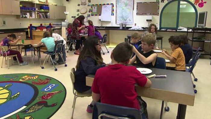 Des élèves sont assis à leur pupitre dans une salle de classe.