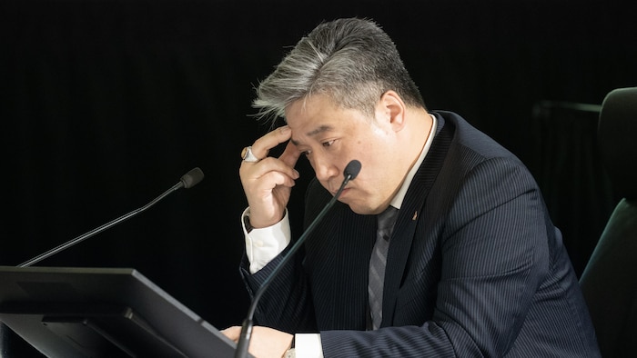 Han Dong, le front reposant sur sa main, assis lors de son témoignage à la commission.
