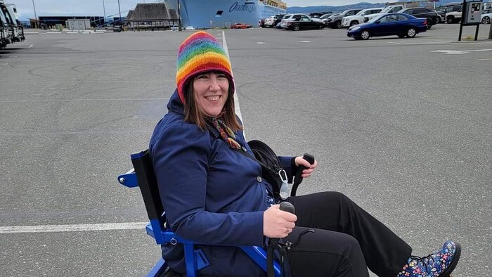 Jennifer Marr a un grand sourire, Elle est sur le quai d'un port devant un navire.