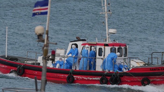 Des gens en combinaison de protection sur un bateau rouge.