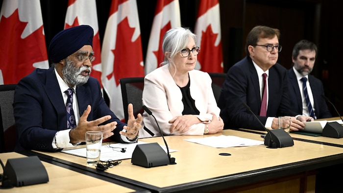 Quatre ministres sont assis à une table en conférence de presse.
