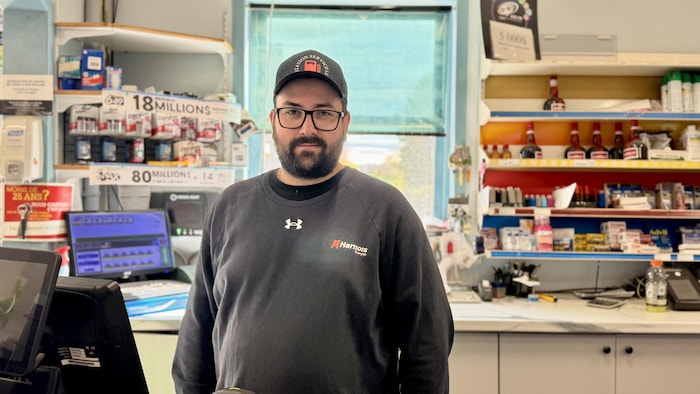 Portrait d'Alexandre Ferguson derrière le comptoir de sa station service.