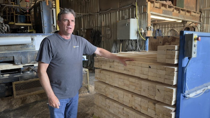Harold Truchon devant une pile de bois.