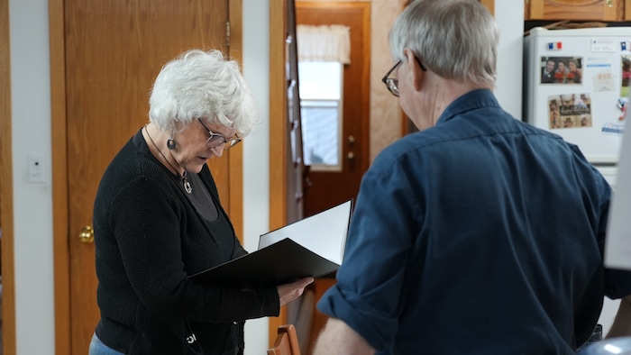 Jocelyne Comeau regarde dans un livre de la collection d'Harold Robicheau.