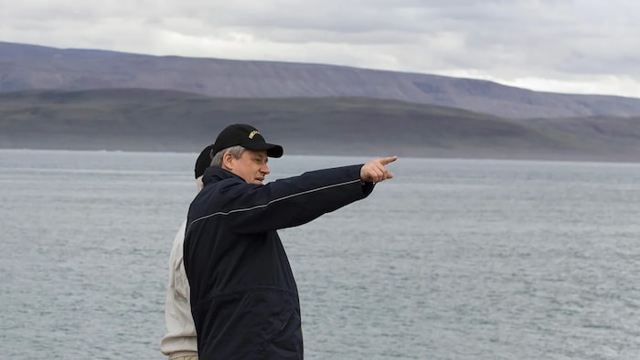 L'ancien premier ministre Stephen Harper regarde et pointe au loin vers la mer dans le port arctique de Nanisivik, au Nunavut, le 10 août 2007.