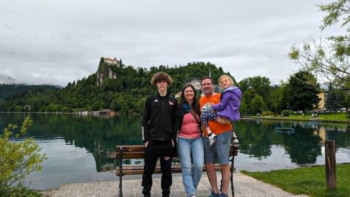 La famille Tanton pose devant un point d'eau, le père porte Harper.