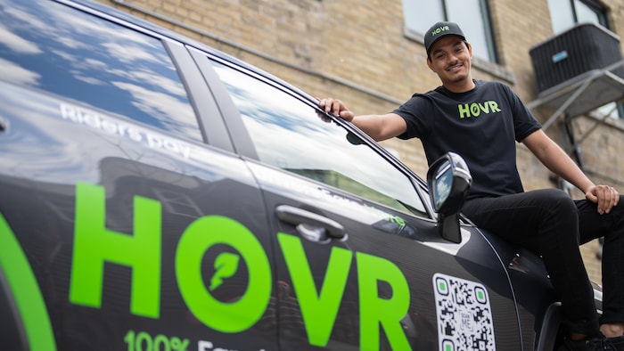 Le fondateur de l'application HOVR, assis sur une voiture.