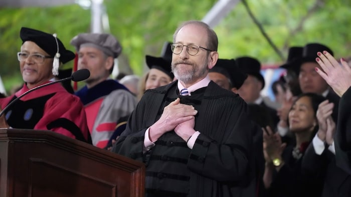 Harvard president Alan Garber, both hands on his chest during a graduating ceremony.