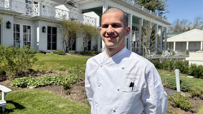 Le chef Alexandre Vachon devant le restaurant Le Hatley du Manoir Hovey sourit à la caméra