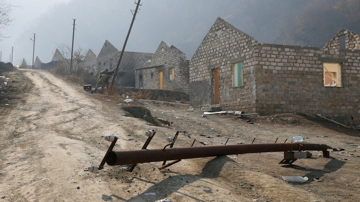 Des maisons partiellement démolies et des soldats en train de détruire des poteaux électriques.
