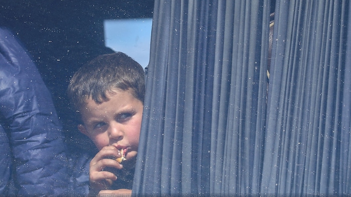 Un garçon mange en regardant par la fenêtre de son autobus.