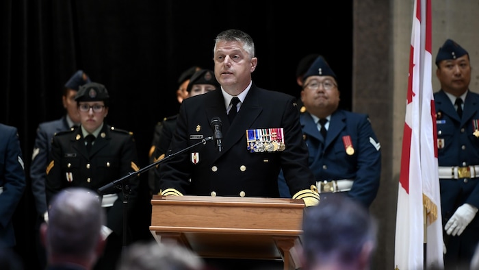 Le vice-amiral Edmundson parlant derrière un micro et un lutrin.