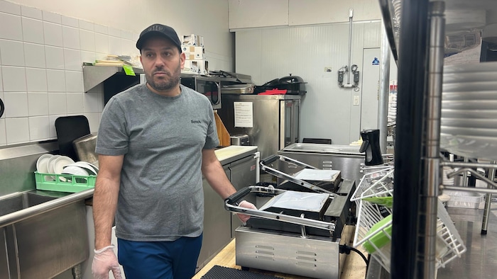 Un homme dans une cuisine de restaurant est interrompu devant deux machines à panini.