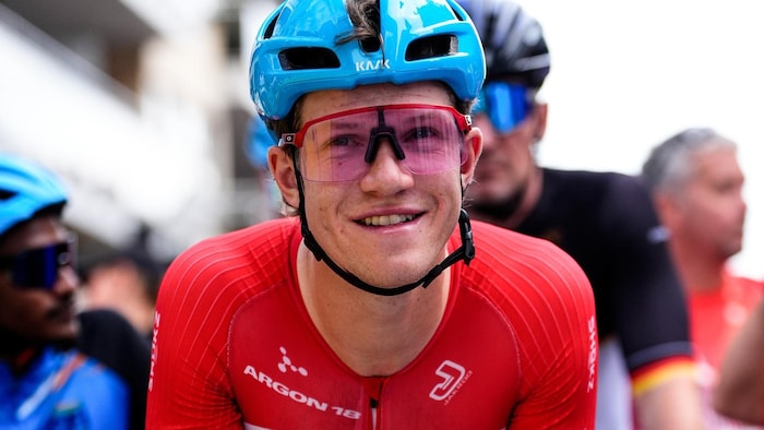 Alexandre Hayward souriant sur la ligne de départ d'une course de cyclisme.