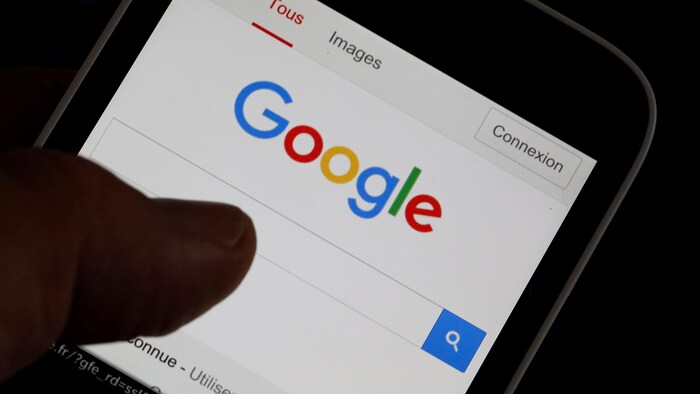 Un homme navigue sur la page d’accueil du site web de Google, sur son téléphone intelligent.