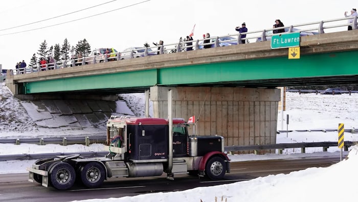People gather atop a bridge as truck drivers protesting against coronavirus disease (COVID-19) vaccine mandates drive in a convoy on the Nova Scotia/New Brunswick provincial boundary in Fort Lawrence, Nova Scotia, Canada, on Jan. 23, 2022. 