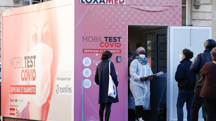 People queue at a mobile COVID-19 testing booth in Paris, France, on New Year's Eve.