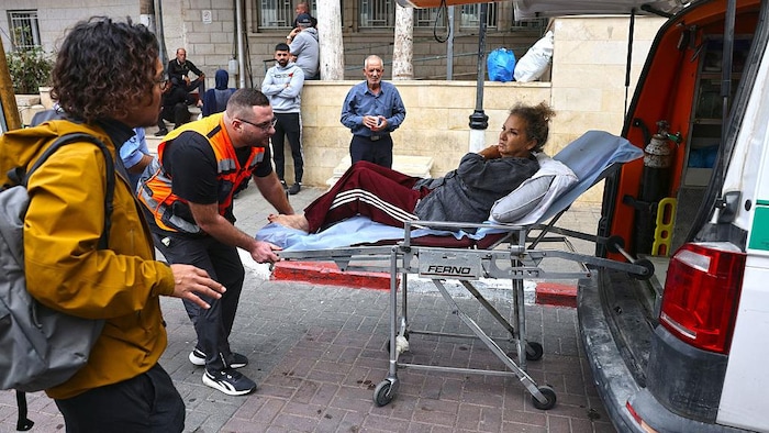 Heidi Levine, assise sur une civière, est transférée dans une ambulance.