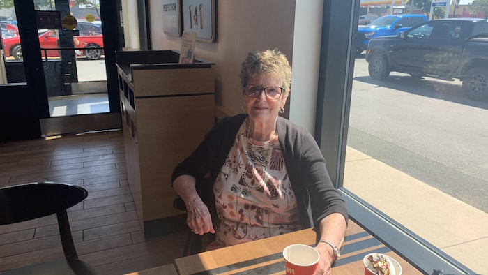 Hélène Benoit pose pour la photo, assise dans un café.