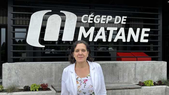 Elle est debout devant une grande vitrine où se trouve le logo du Cégep de Matane.