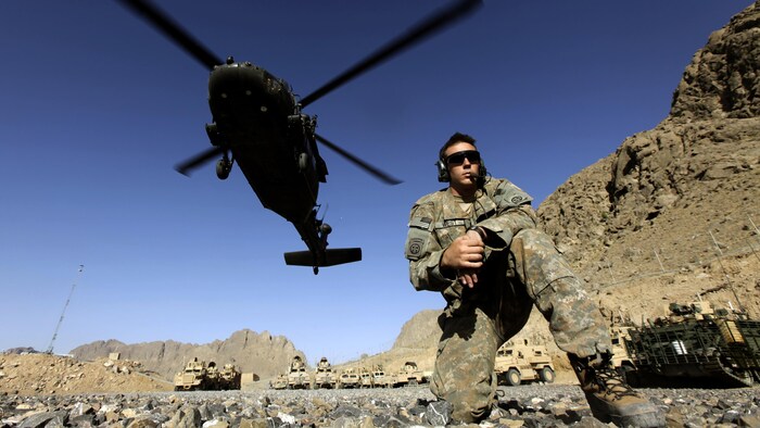 Un soldat se tient sous l'hélicoptère.