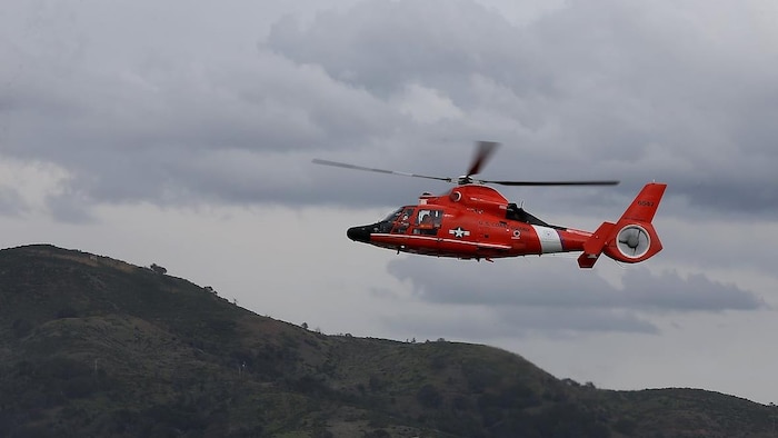 Un hélicoptère de la Garde côtière américaine vole dans le ciel.