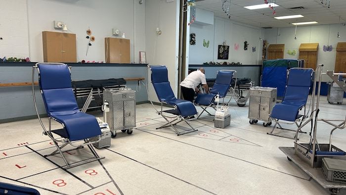 Une personne place des chaises dans un gymnase.