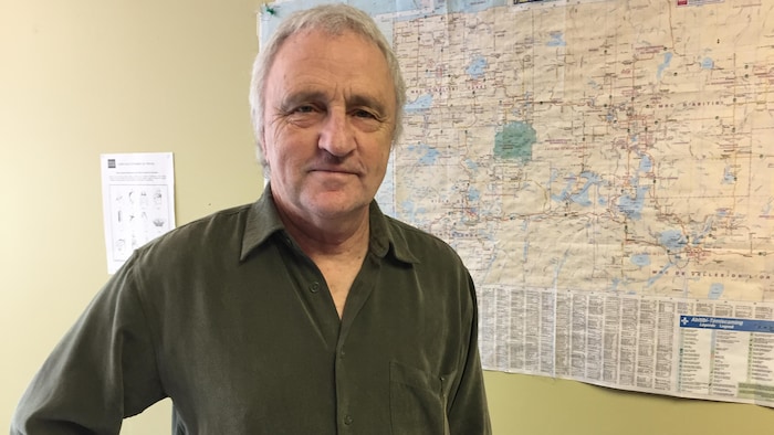 Henri Jacob pose pour la caméra devant une carte.