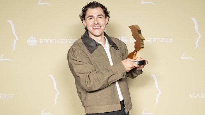 Un homme tient un trophée. 