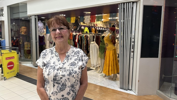 Portrait de Henriette Hayes posant devant un magasin du centre d'achat Elm Place.