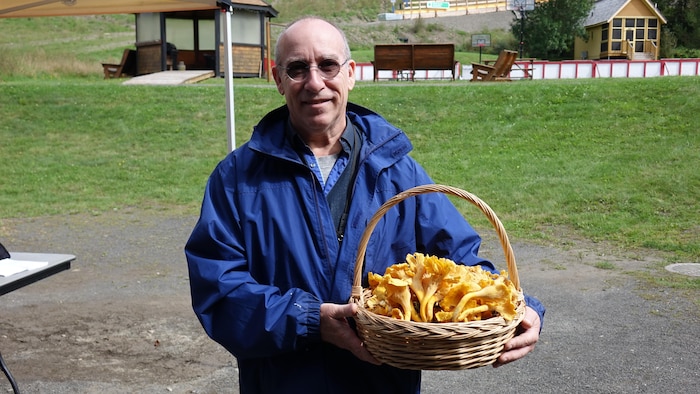 Portrait de Herman Lambert tenant un panier de champignons dans ses mains.