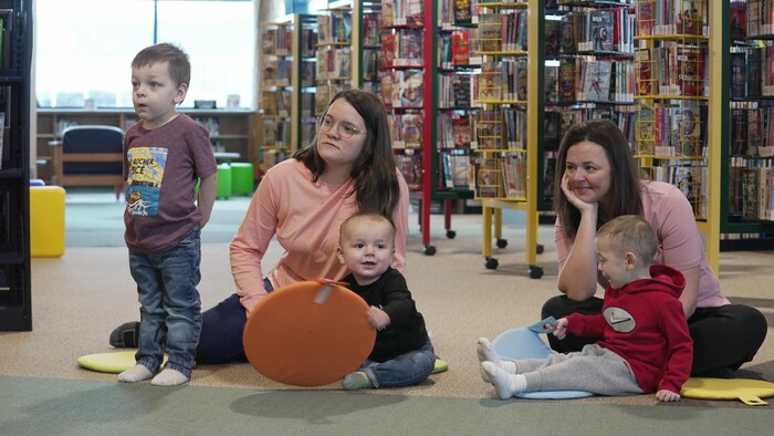 Des enfants et des mères dans une bibliothèque.