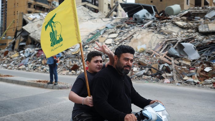 Un jeune brandit le drapeau du Hezbollah en passant devant des immeubles détruits dans la banlieue sud de Beyrouth. 