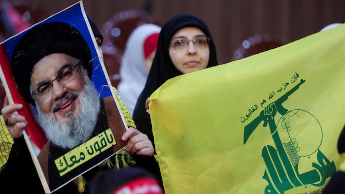 Des partisans du Hezbollah portent un drapeau et une photo du chef du Hezbollah, Sayyed Hassan Nasrallah, lors d'un rassemblement dans la banlieue sud de Beyrouth, au Liban.