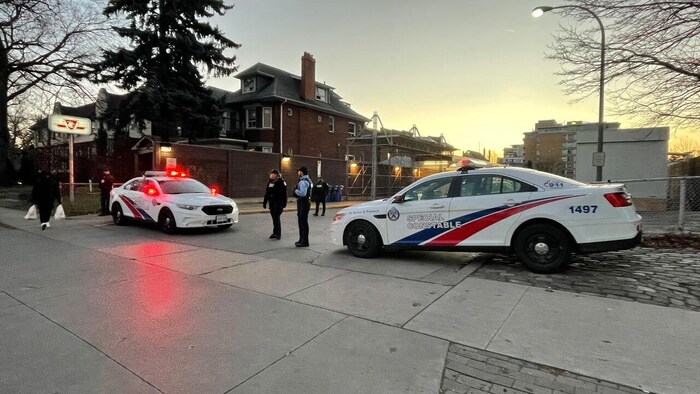 Un policier et un agent de sécurité du métro et leurs véhicules bloquent l'entrée de la station.