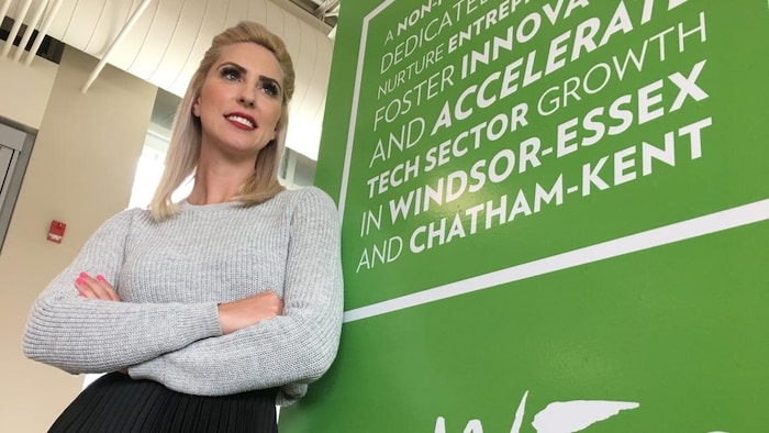 Yvonne Pilon est debout devant une pancarte de son entreprise WETech Alliance