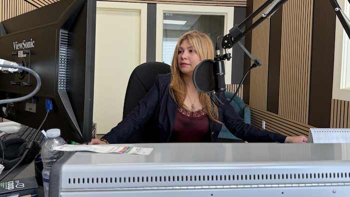 Derrière la console d'un studio de radio, Hind Dekkar regarde un écran d'ordinateur.