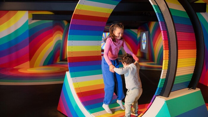 Deux enfants qui jouent dans une grande roue couleur arc-en-ciel.
