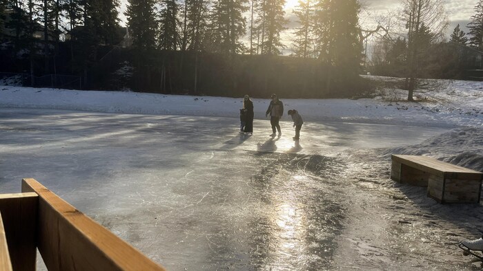 Une famille glisse sur une patinoire extérieure.
