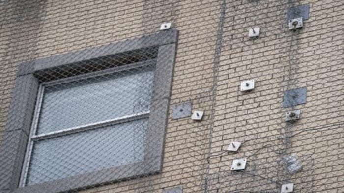  Une façade avec une fenêtre derrière un grillage.