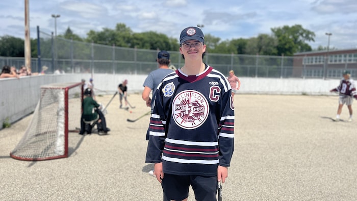 Un jeune homme avec un baton de hockey.