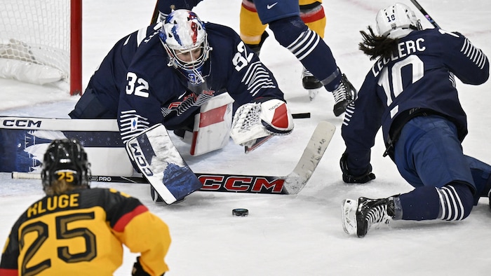 La gardienne, accroupie sur la glace, utilise son bâton.