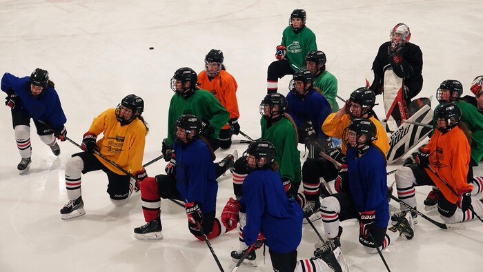 Des joueuses de hockey en tenue avec un genou à terre, sur la glace.