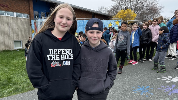 Meredith et Felix Loucka sont debout devant des élèves près de l'école.