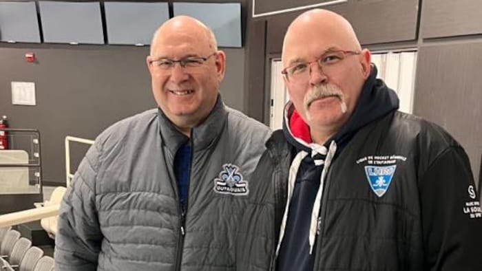 Deux dirigeants d'une association de hockey prennent la pose dans un aréna.